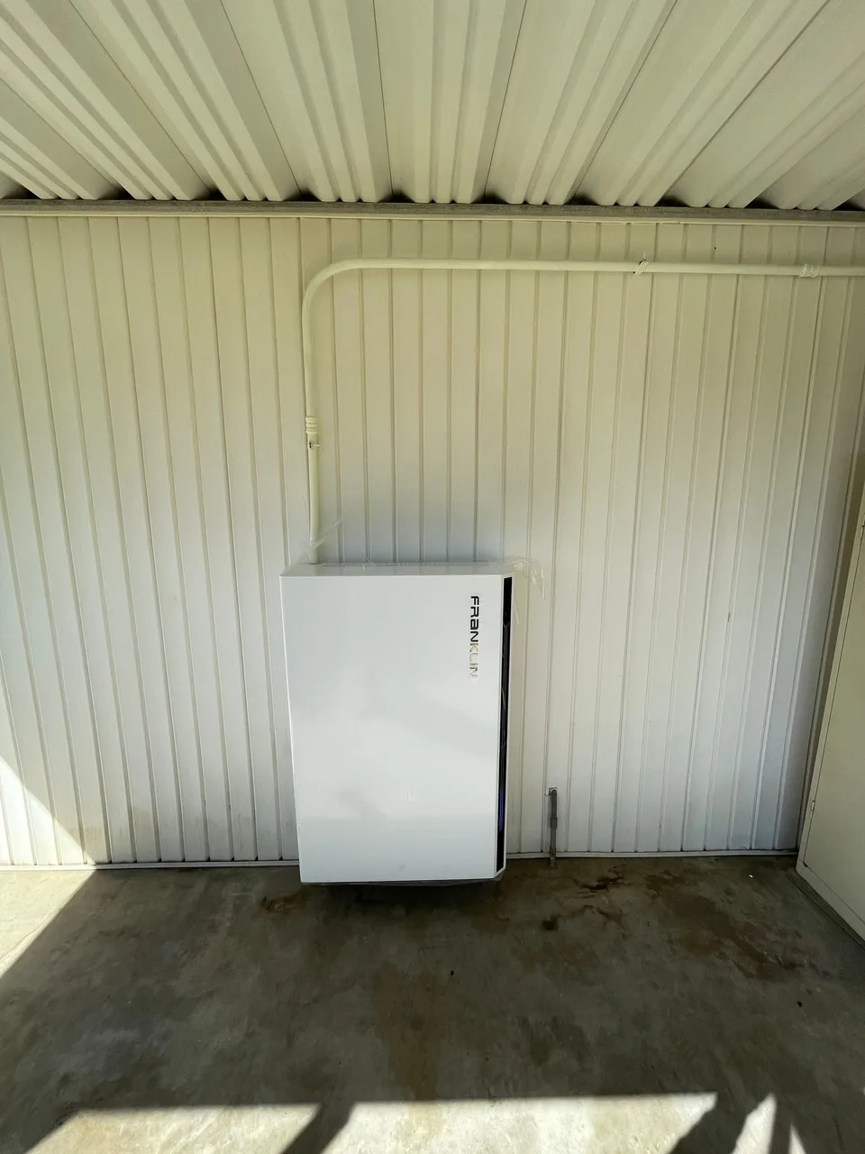 A single Franklin battery mounted low on a light-colored exterior wall beneath a patio cover.