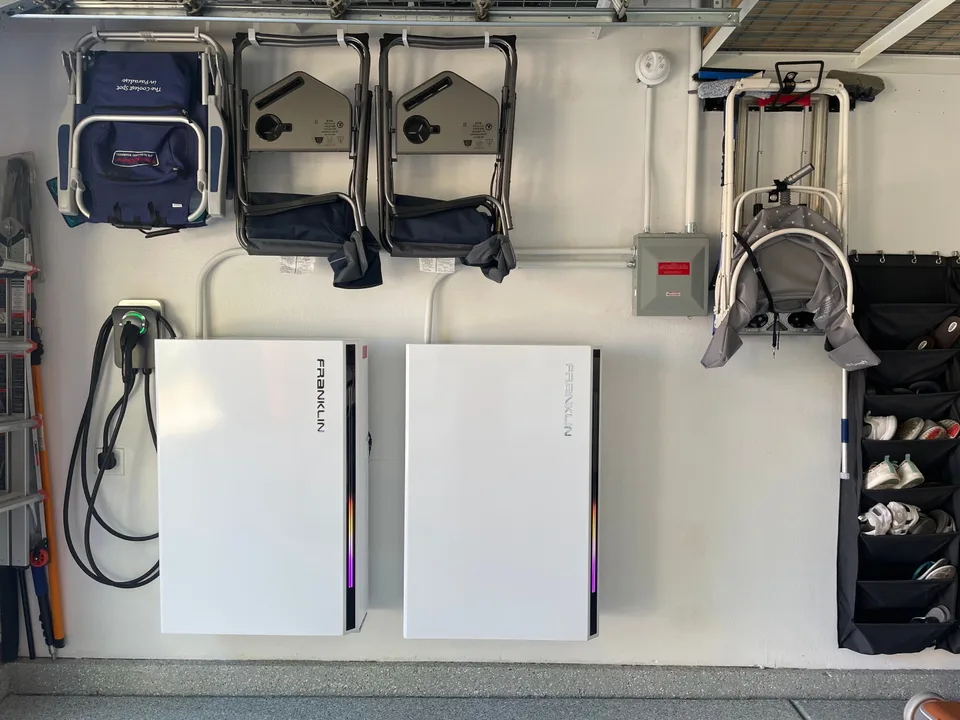 Two Franklin batteries mounted beneath garage storage, with electrical conduit routed above the units.