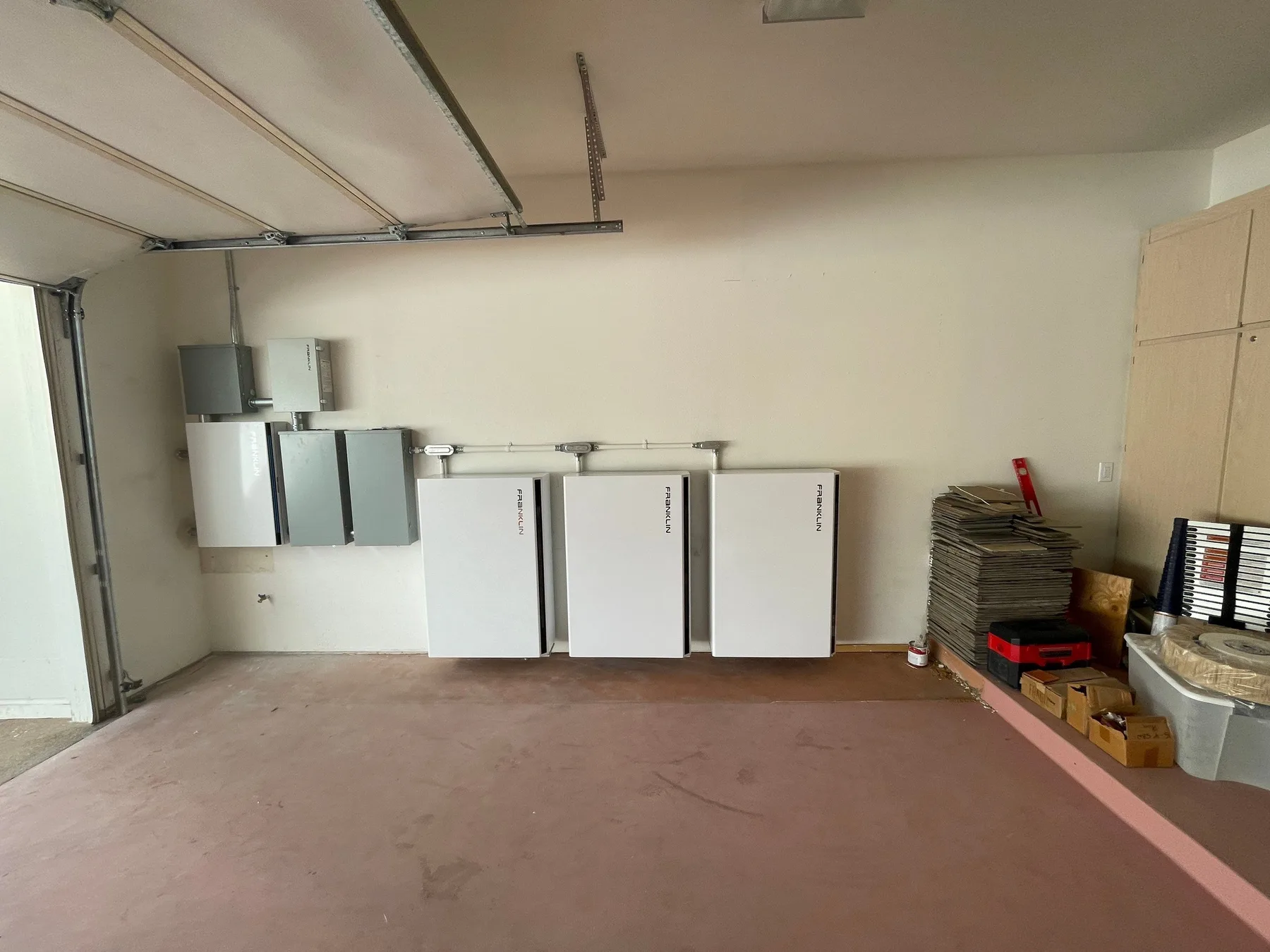 Three Franklin batteries mounted in a row along a garage wall.