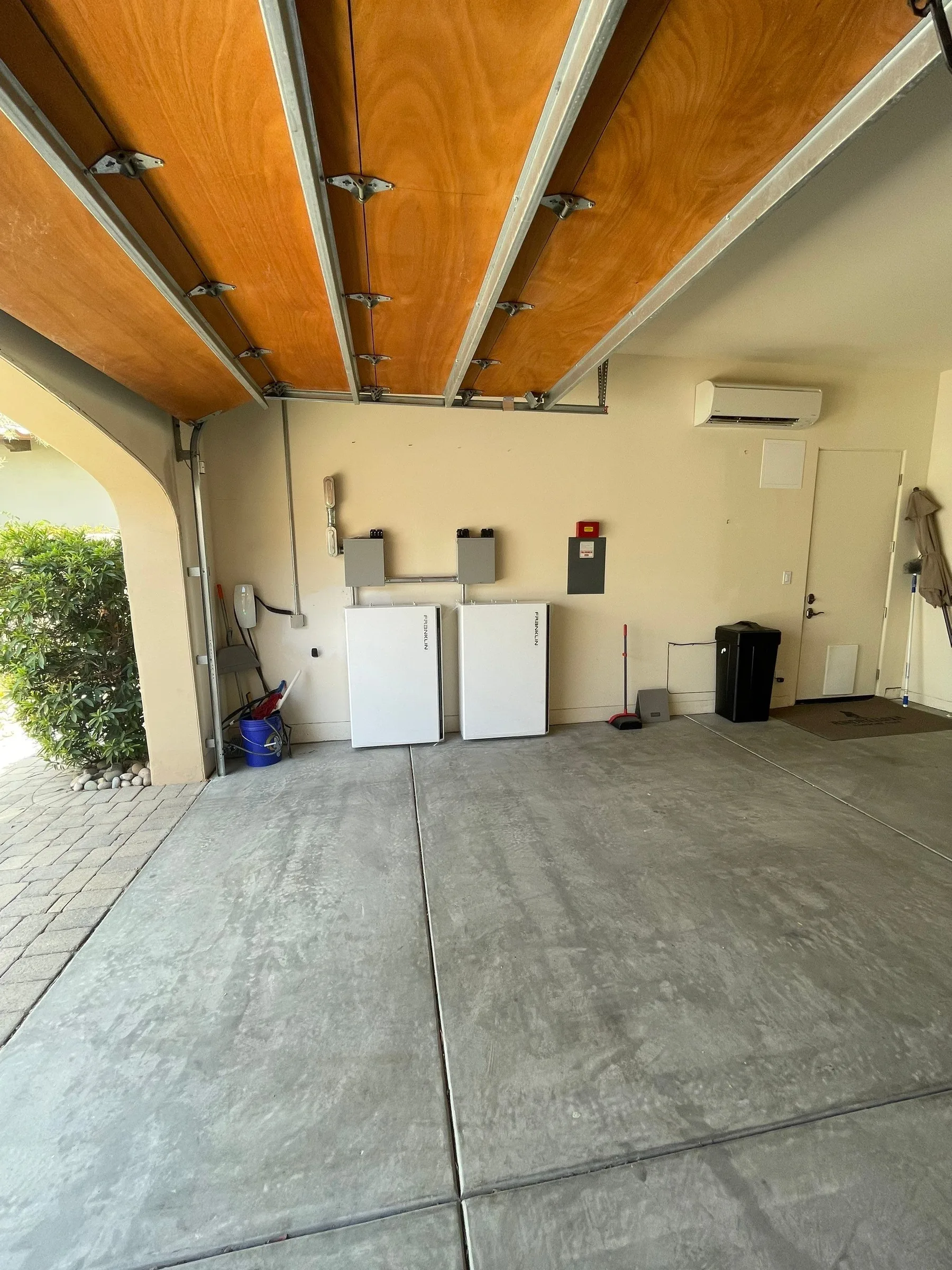 Two Franklin batteries mounted along the back wall of a garage with a wooden overhead door.